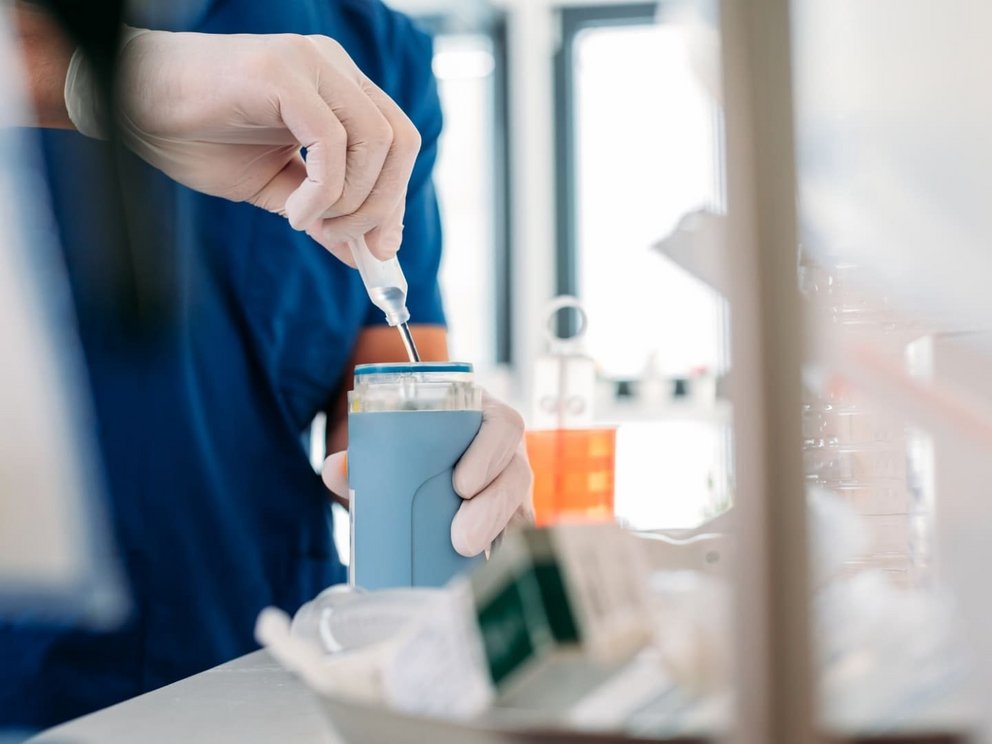 zu Fachartikeln aus dem Zentrum für Beatmung und Intensivpflege (ZBI) Pflegekraft in blauer Arbeitskleidung im Fachpflegezentrum der ZBI Gruppe die eine Pipette benutzt, um eine Flüssigkeit in einen kleinen Behälter zu geben für eine Analyse